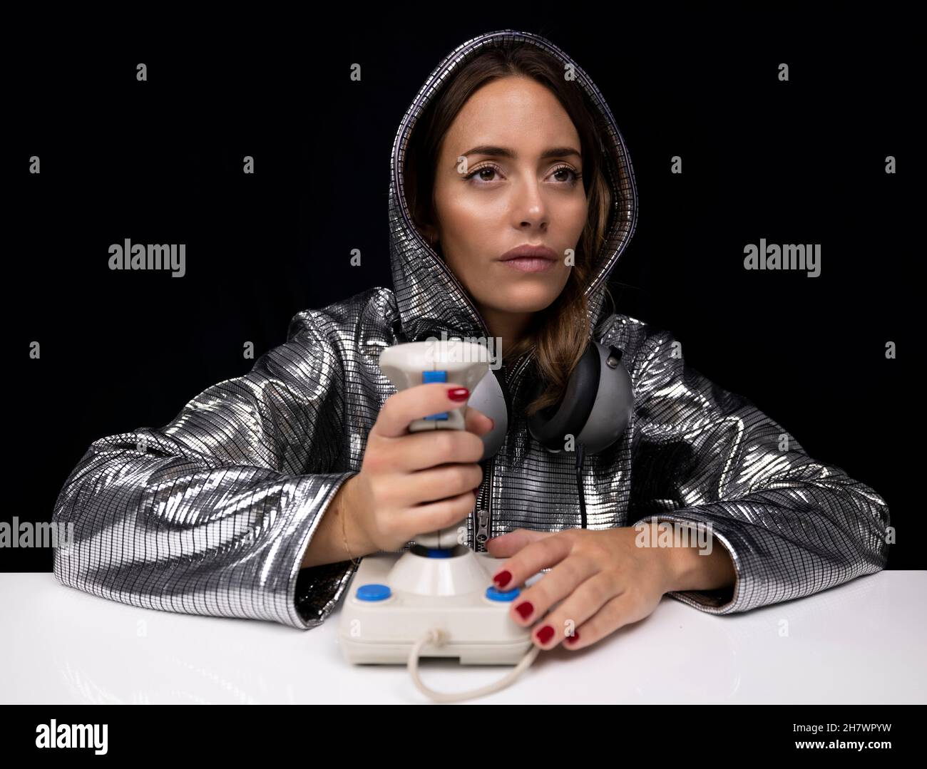 Mujer con traje de plata y joystick de ordenador Foto de stock