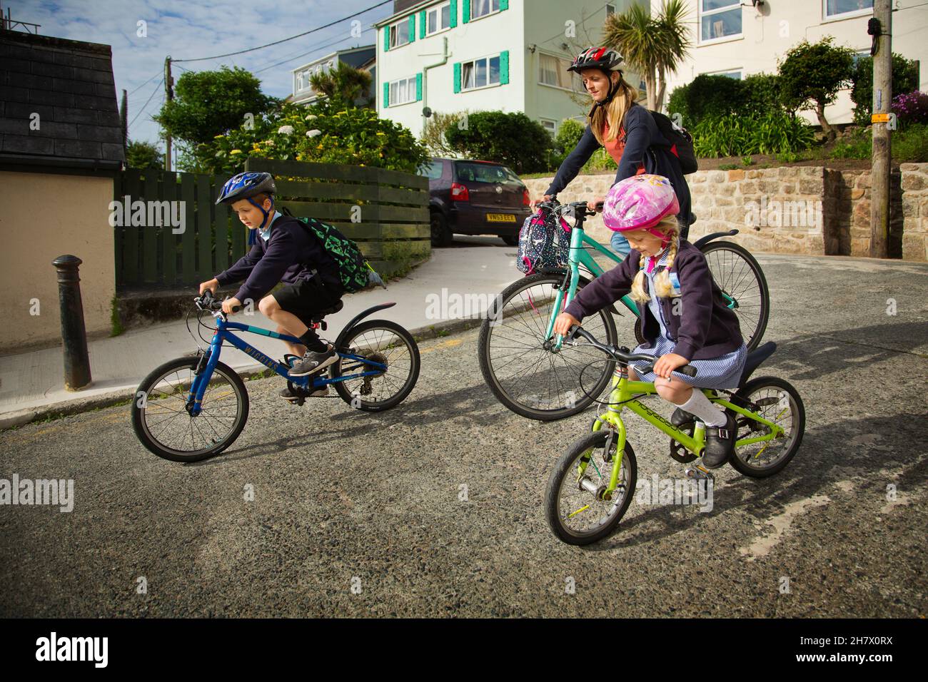 Niños en bicicleta a la escuela con su madre, scilly Isles, Reino Unido Foto de stock
