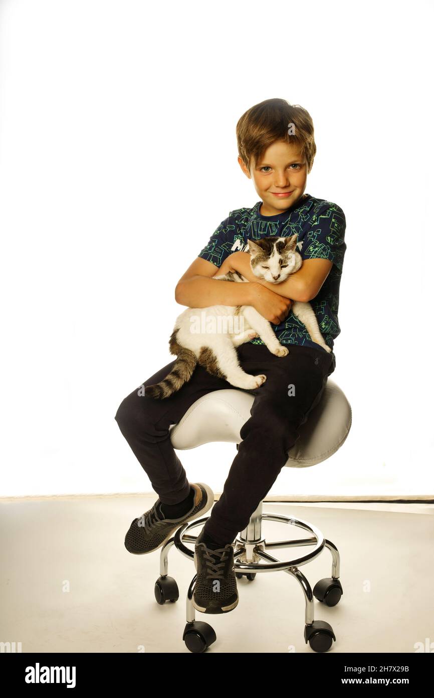 Un niño pequeño sosteniendo a su gato mascota Foto de stock