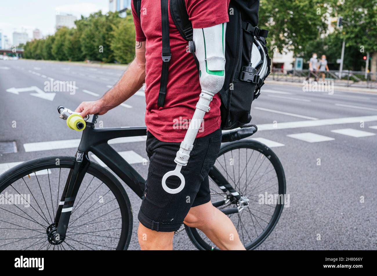 Vista lateral del hipster masculino recortado irreconocible con prótesis de  brazo caminando con bicicleta en el cruce de la ciudad Fotografía de stock  - Alamy