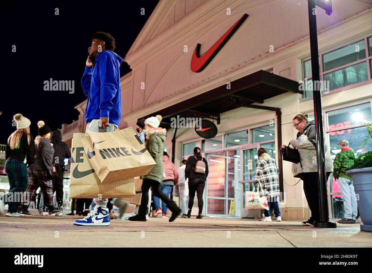 Un con bolsas Nike habla por teléfono frente a una tienda Nike mientras las ventas de Black Friday comienzan en Outlet Shoppes of the Bluegrass en Simpsonville, Kentucky, EE.UU., 26 de