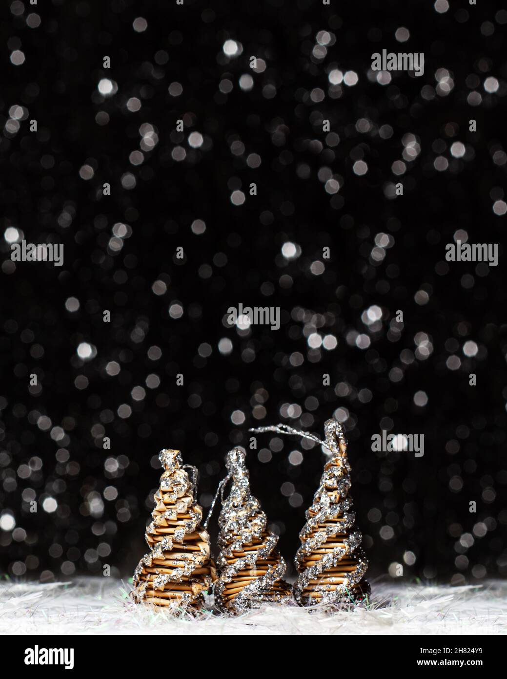 Adornos navideños vista de tres árboles de madera coloreados en solver brillo en las puntas y el erizo blanco sobre fondo oscuro con colores plata bokeh A. Foto de stock