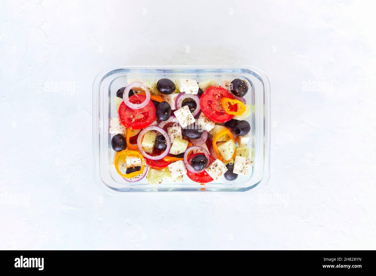 Fiambrera con ensalada griega sobre fondo blanco Foto de stock