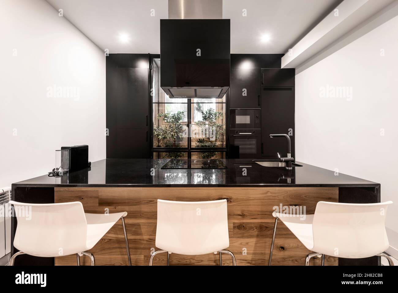 Isla de cocina con encimera de mármol negro, campana extractora negra y  muebles a juego en apartamento de vacaciones Fotografía de stock - Alamy