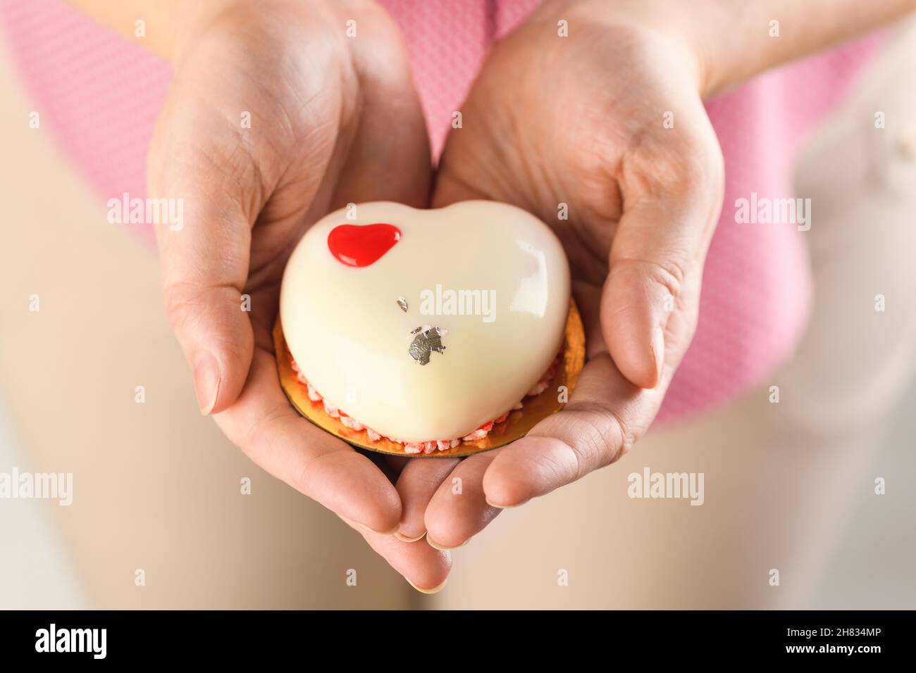 Cupcake en forma de corazón primer plano. Mousse pastel en forma de corazón en las manos de una chica para el día de San Valentín y 14th de febrero Foto de stock