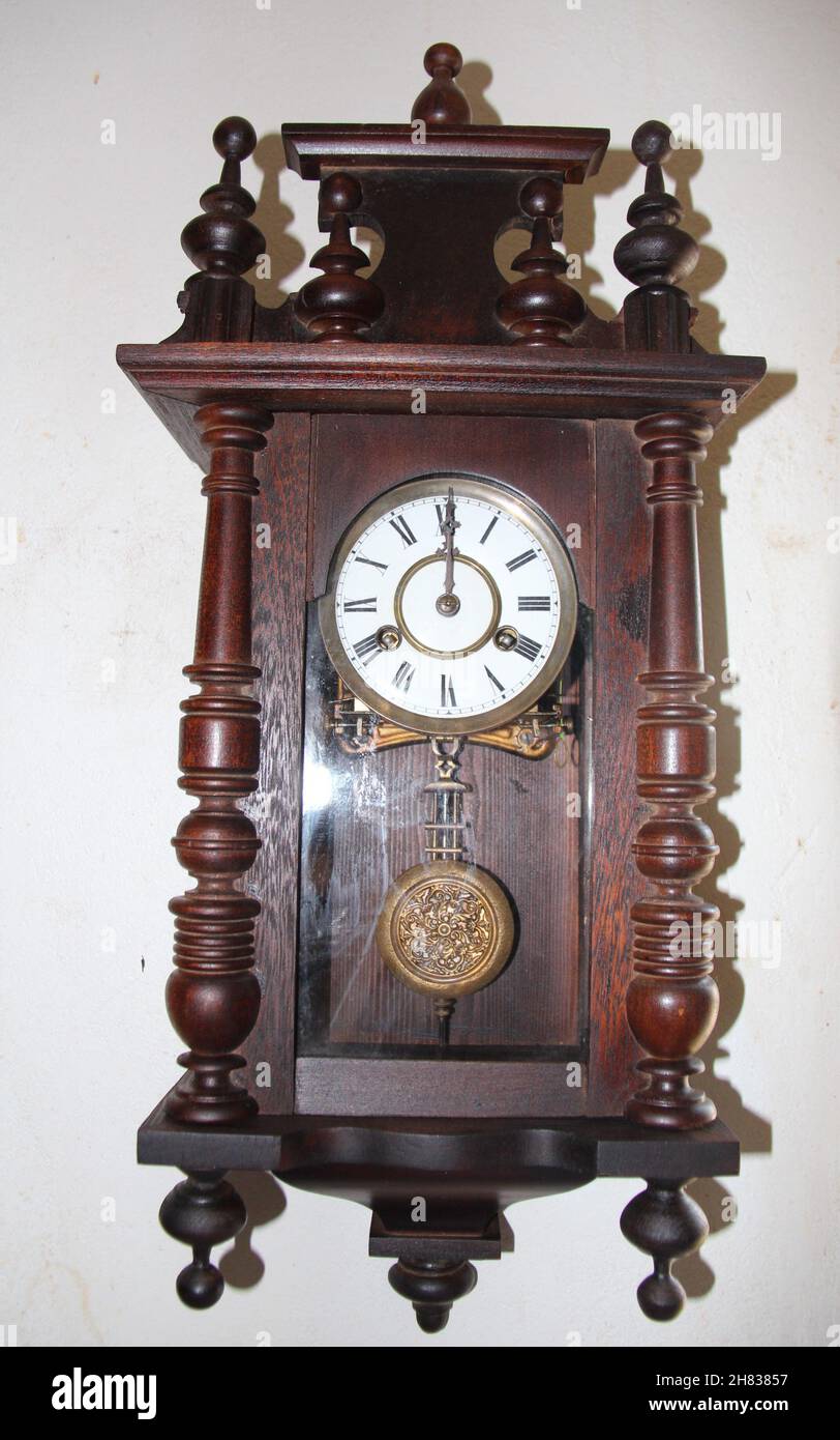 Antiguo reloj de madera con péndulo y cuerda sobre una pared blanca, pieza  de coleccionista Fotografía de stock - Alamy