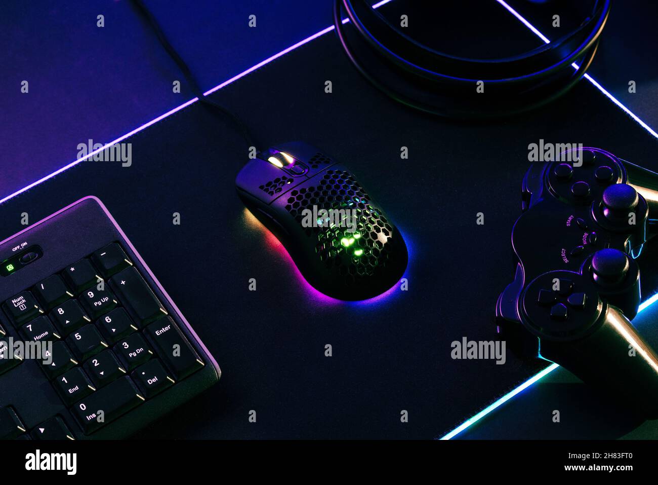 Composición de juegos con ratón, teclado, jopad y auriculares en la alfombrilla LED para juegos Foto de stock