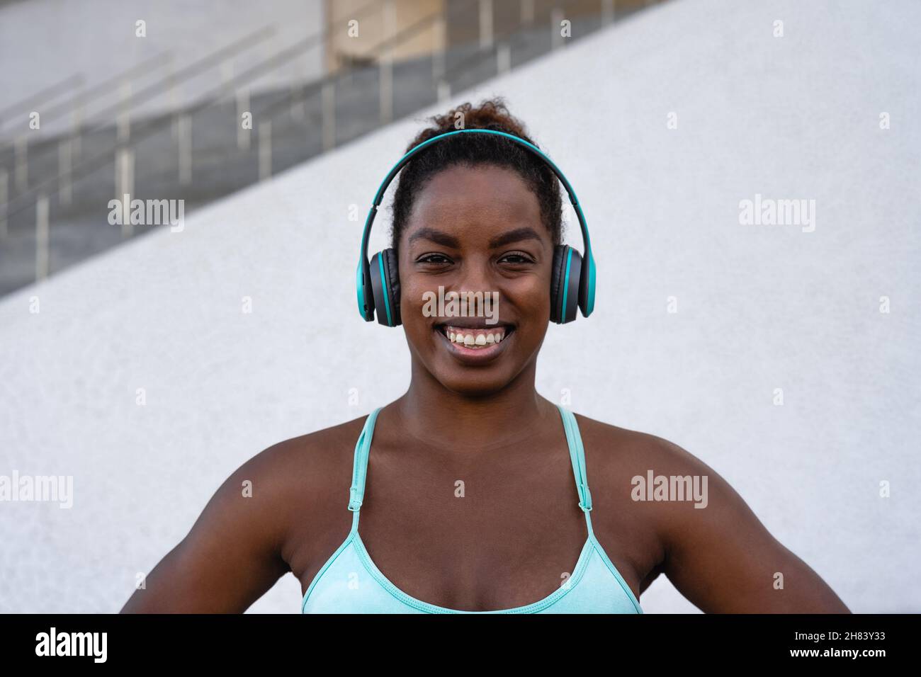 Mujer joven africana en forma escuchando música con auriculares durante la sesión de ejercicio al aire libre - Sport people concepto de estilo de vida Foto de stock