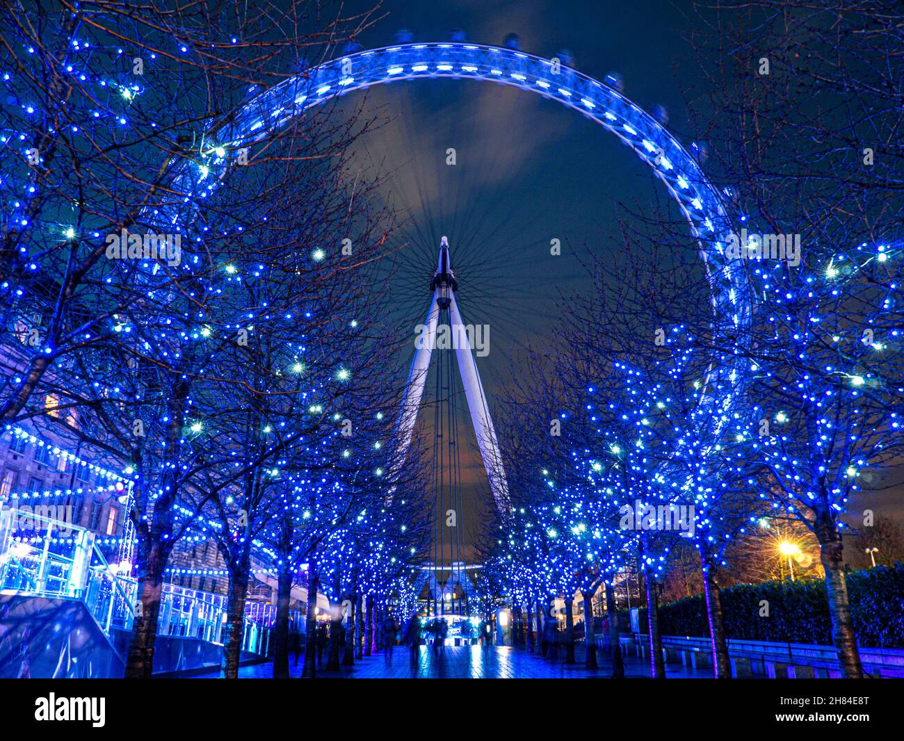 London Eye con luces brillantes azules navideñas de árboles en la noche South Bank London, England UK Foto de stock