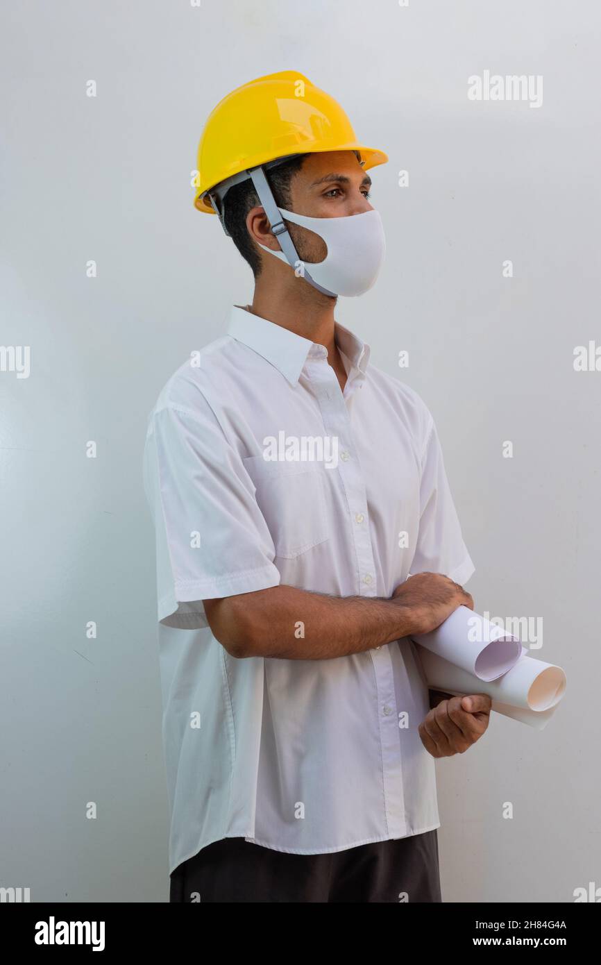 Trabajador con casco y máscara pandémica aislados sobre fondo blanco. Hombre  negro sosteniendo la hoja de extensión Fotografía de stock - Alamy