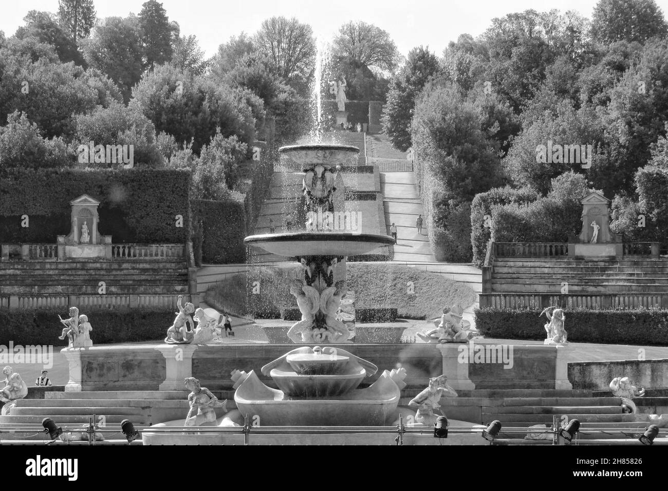 Foto en escala de grises de una fuente en el parque de los jardines Boboli con denso fondo de árboles en Florencia, Italia Foto de stock