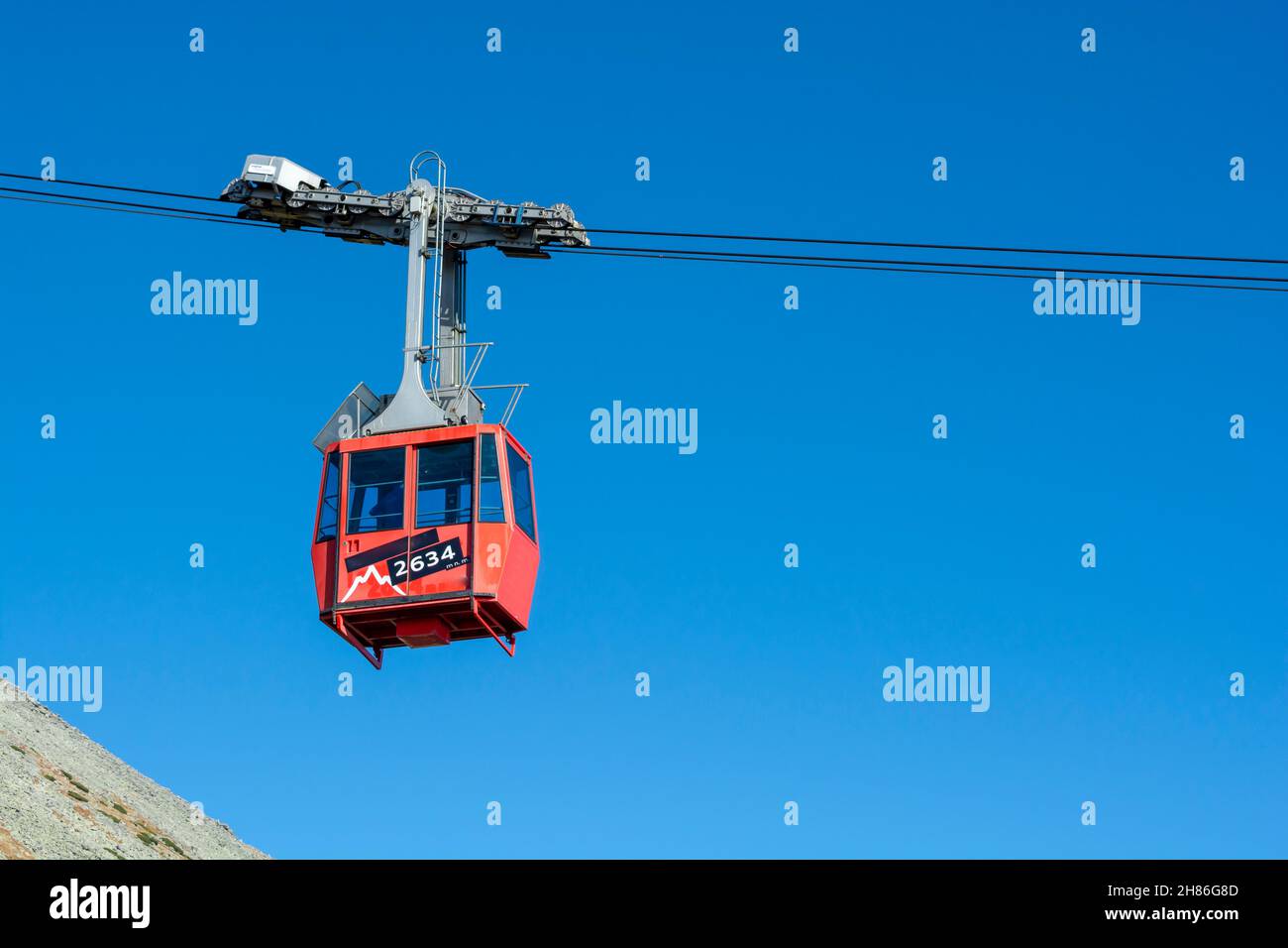 Un teleférico rojo en su camino de Skalnate pleso a Lomnicky pico. Góndola roja que sube hasta el pico Lomnica en las montañas de los Altos Tatras. Eslovaquia. Foto de stock