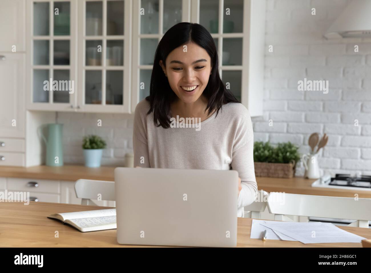 Una mujer asiática mira el portátil sonriendo leer noticias de bienes Foto de stock