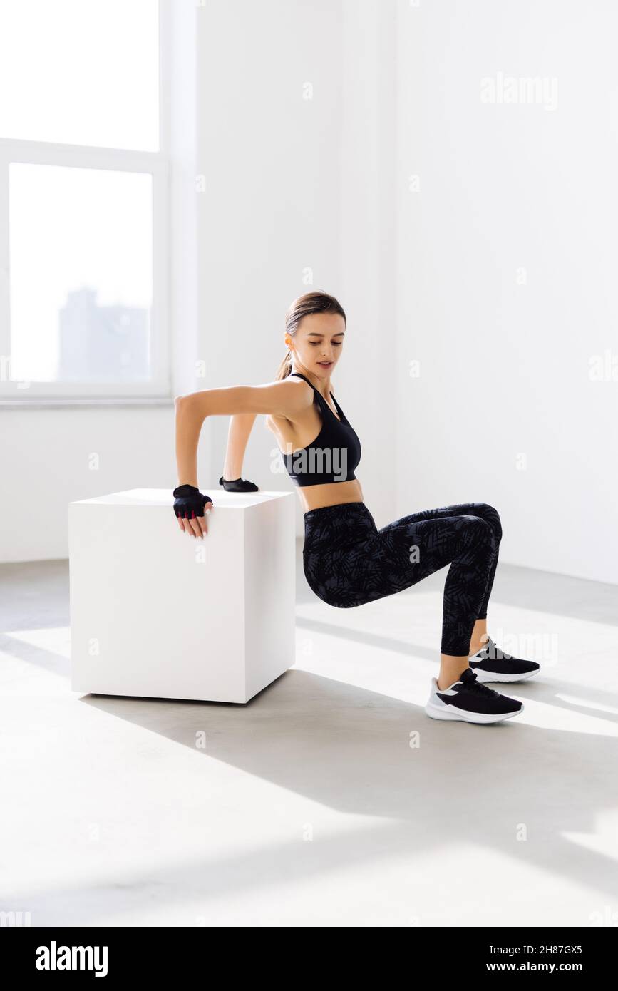 Mujer joven haciendo un ejercicio de salto de caja. Una mujer muscular  haciendo una sentadilla en el gimnasio Fotografía de stock - Alamy