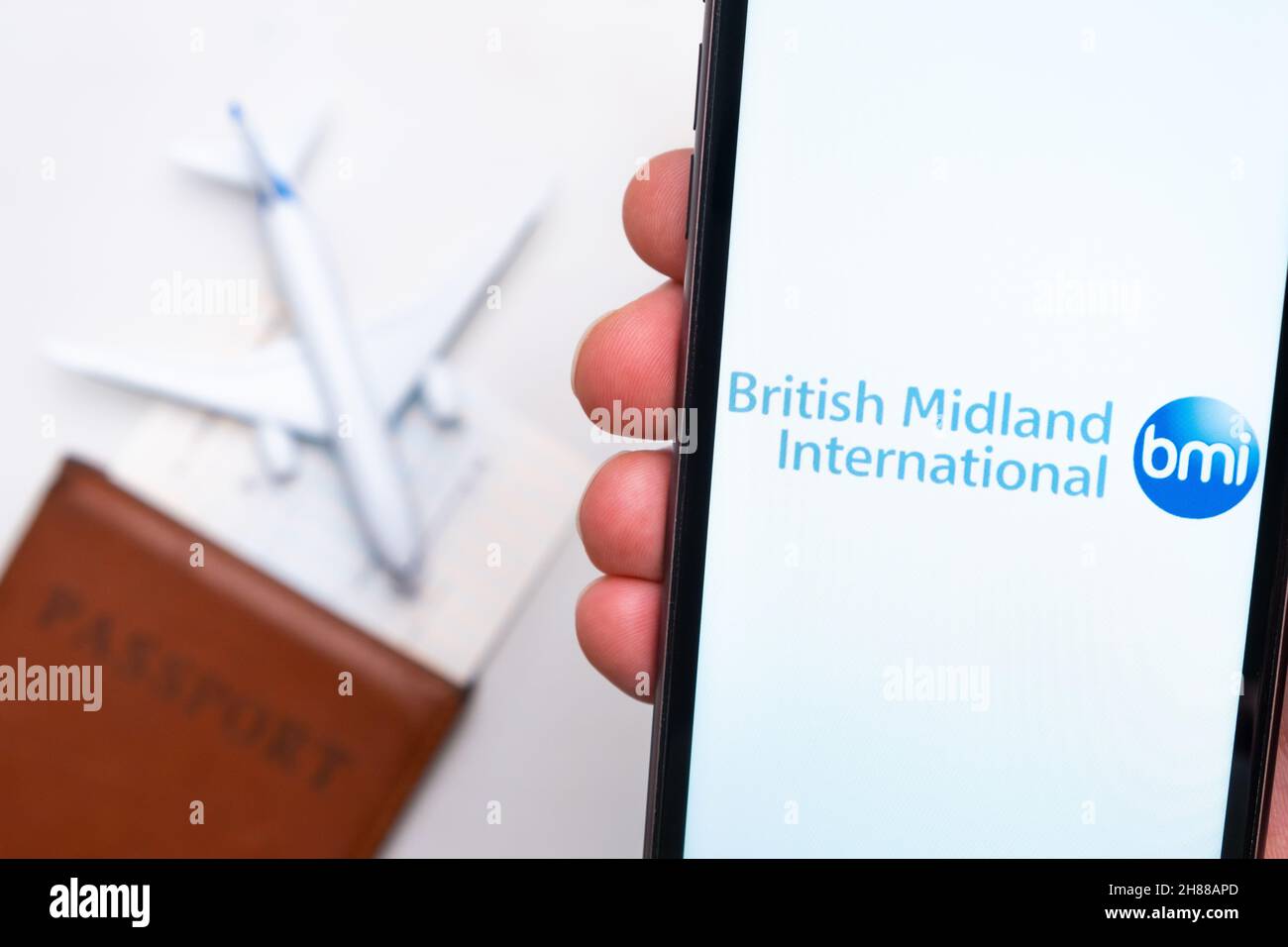 Logotipo de la aplicación British Midland International Airlines en la pantalla del teléfono móvil. Imagen borrosa de un avión, un pasaporte y una tarjeta de embarque en el fondo. 2021 de noviembre, San Francisco, EE.UU Foto de stock