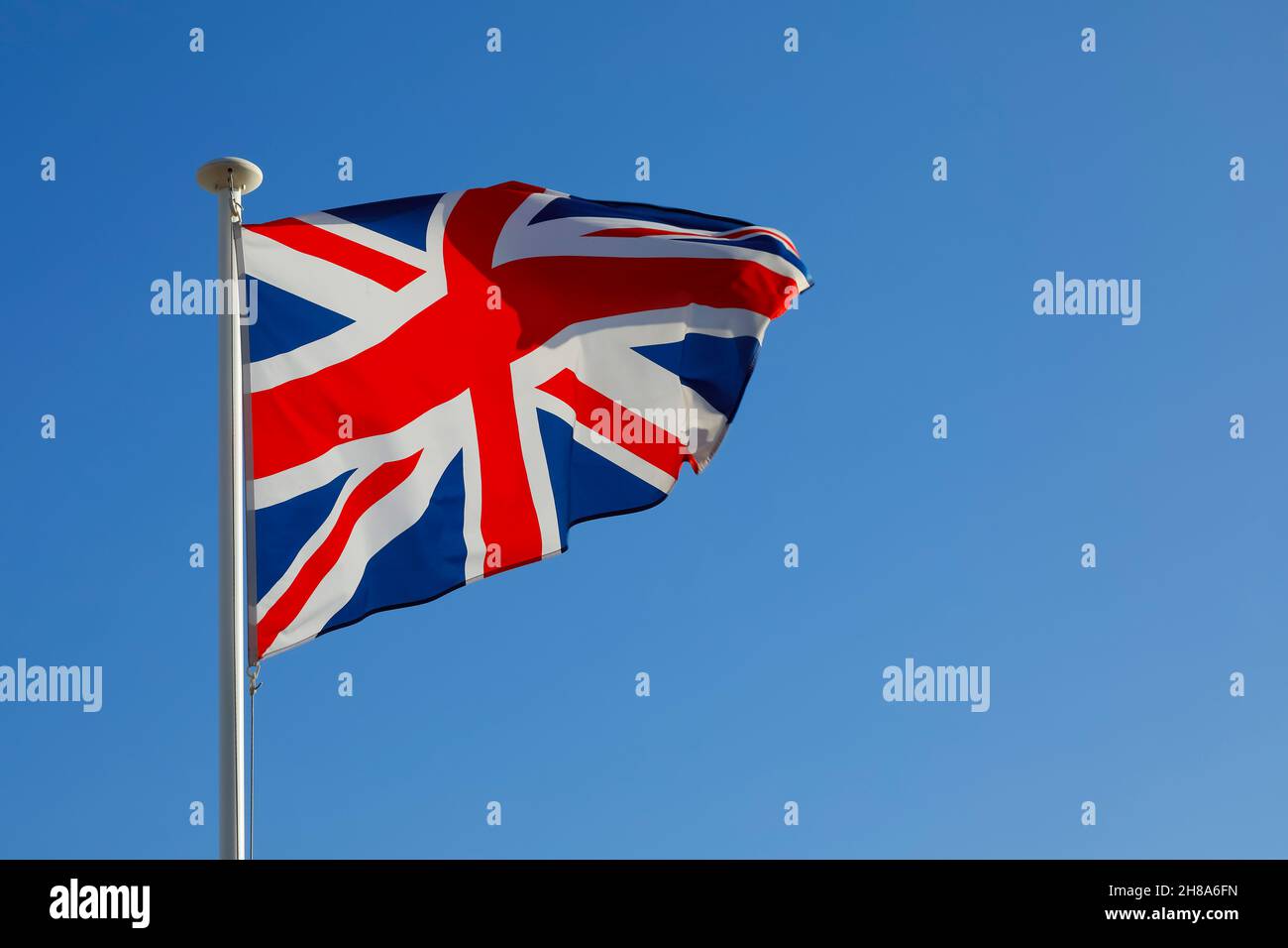 La Bandera Nacional del Reino Unido revoloteaba en el viento y se puede ver contra un cielo azul durante un día soleado. Foto de stock