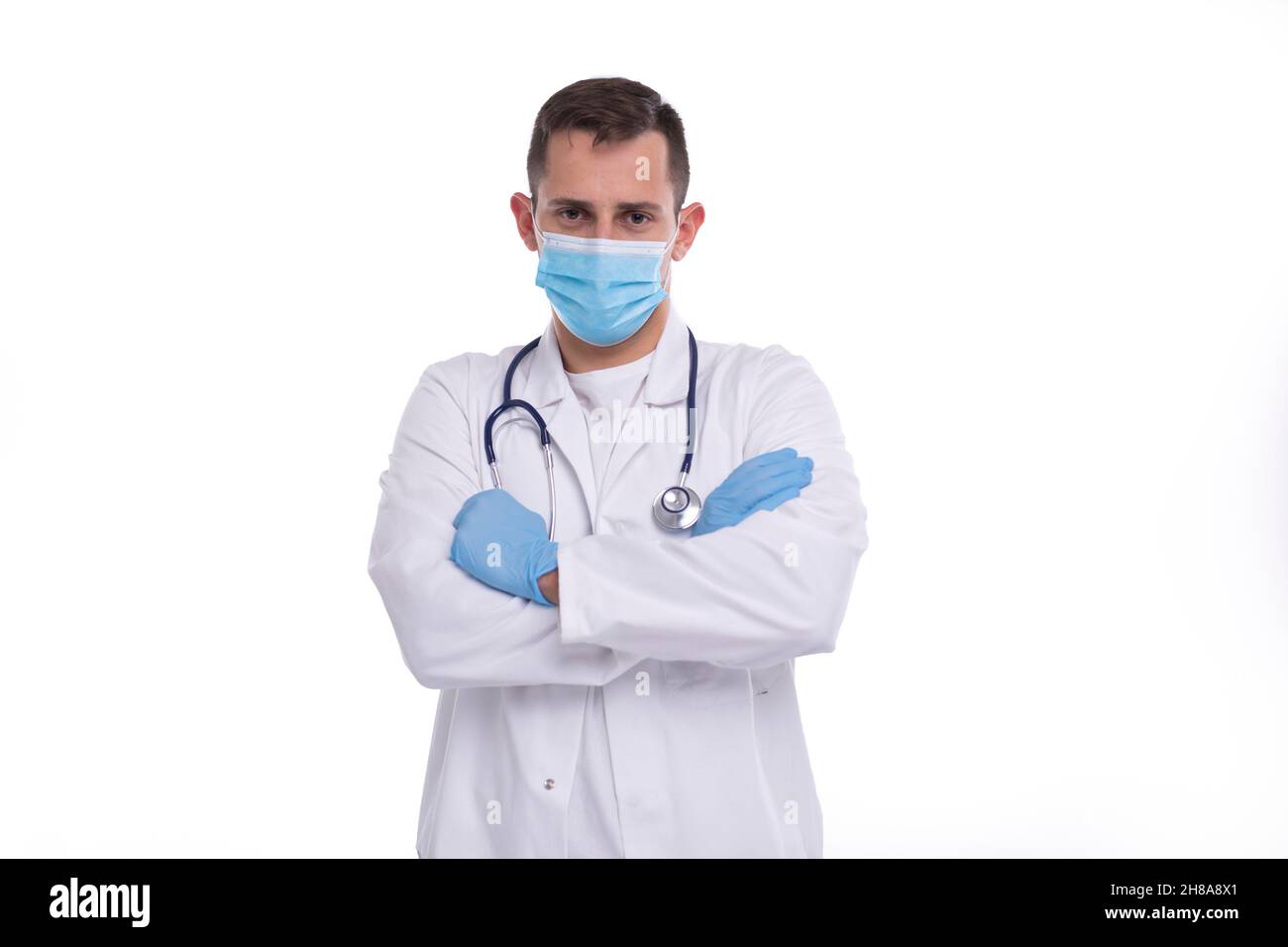 Médico con máscara médica y guantes cruzó las manos aisladas. Hombre Doctor Manos Cruzadas Concepto Médico. Foto de stock