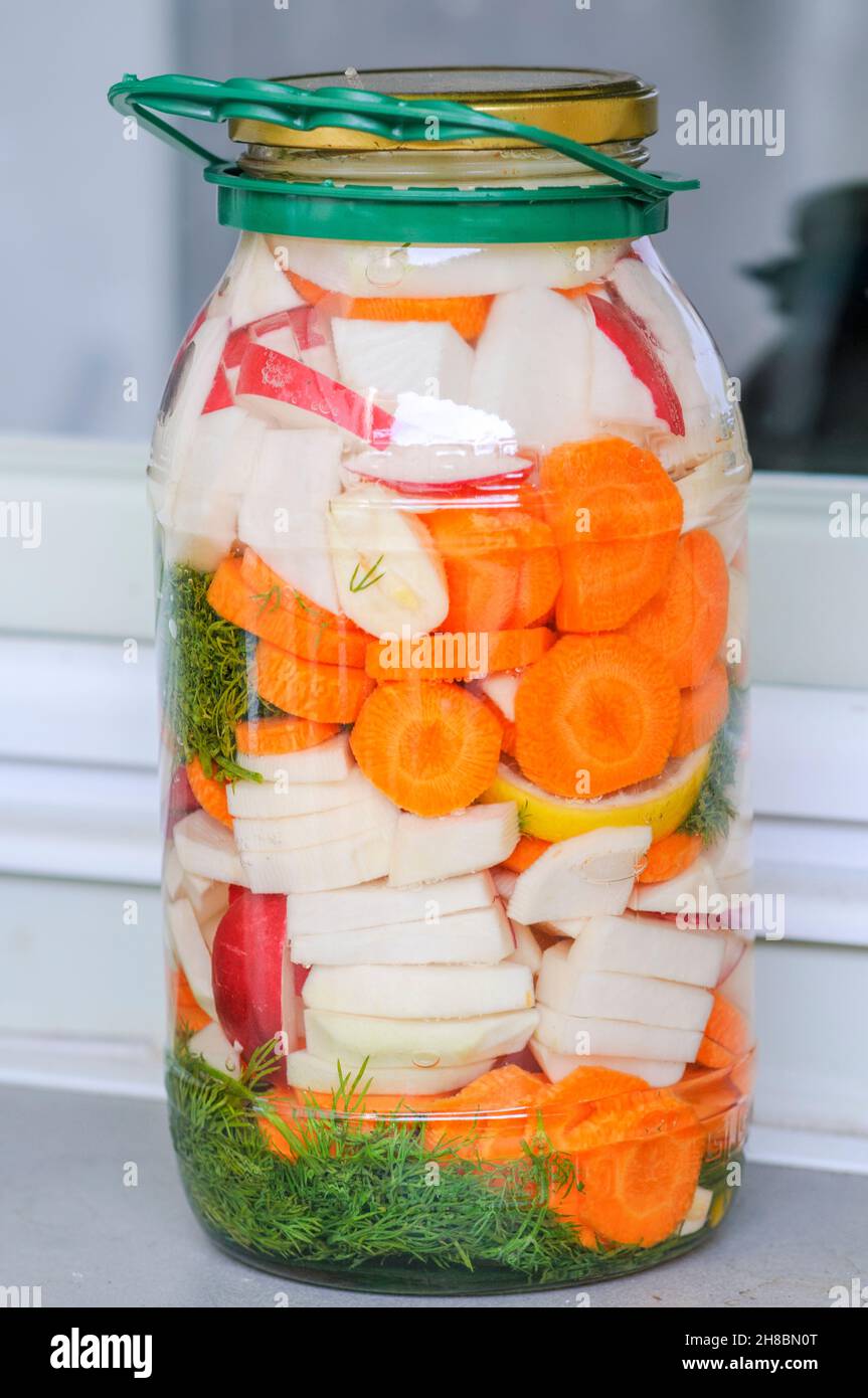 Jarra con variedad de verduras encurtidas caseras expuestos a luz sobre el alféizar de la cocina Foto de stock