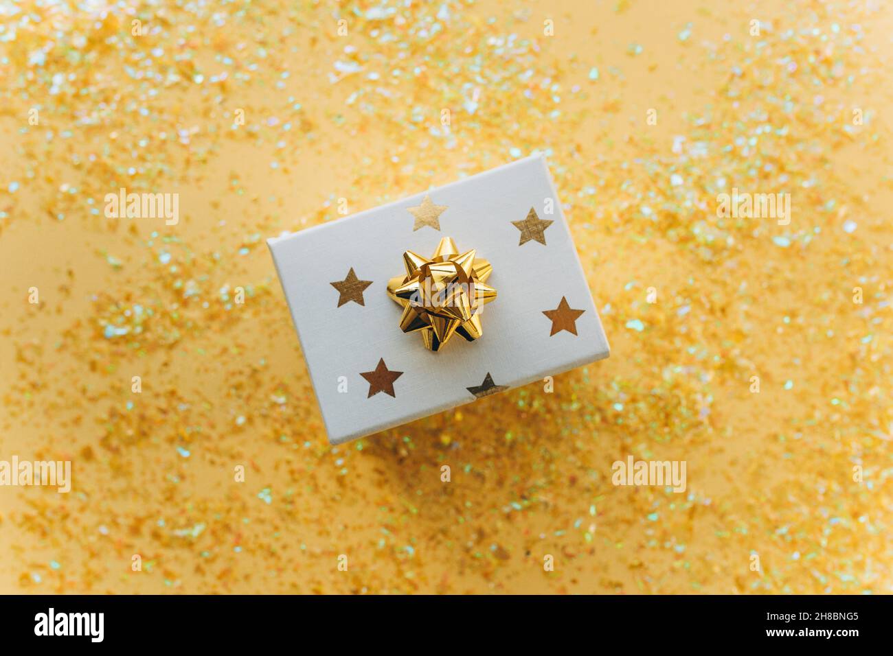Caja blanca de regalo con cinta dorada con piel y confeti sobre fondo blanco. El concepto de un regalo, un año nuevo, un fondo festivo. Plano, vista superior Foto de stock