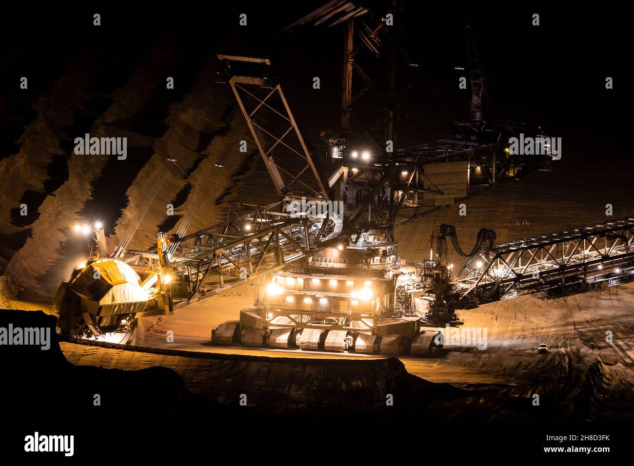 Equipo pesado de minería en funcionamiento en una mina a cielo abierto al atardecer. Foto de stock
