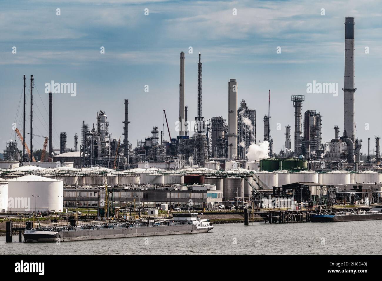 Refinería de petróleo, fábrica de plantas petroquímicas industriales y barcazas en un puerto de embarque industrial Foto de stock