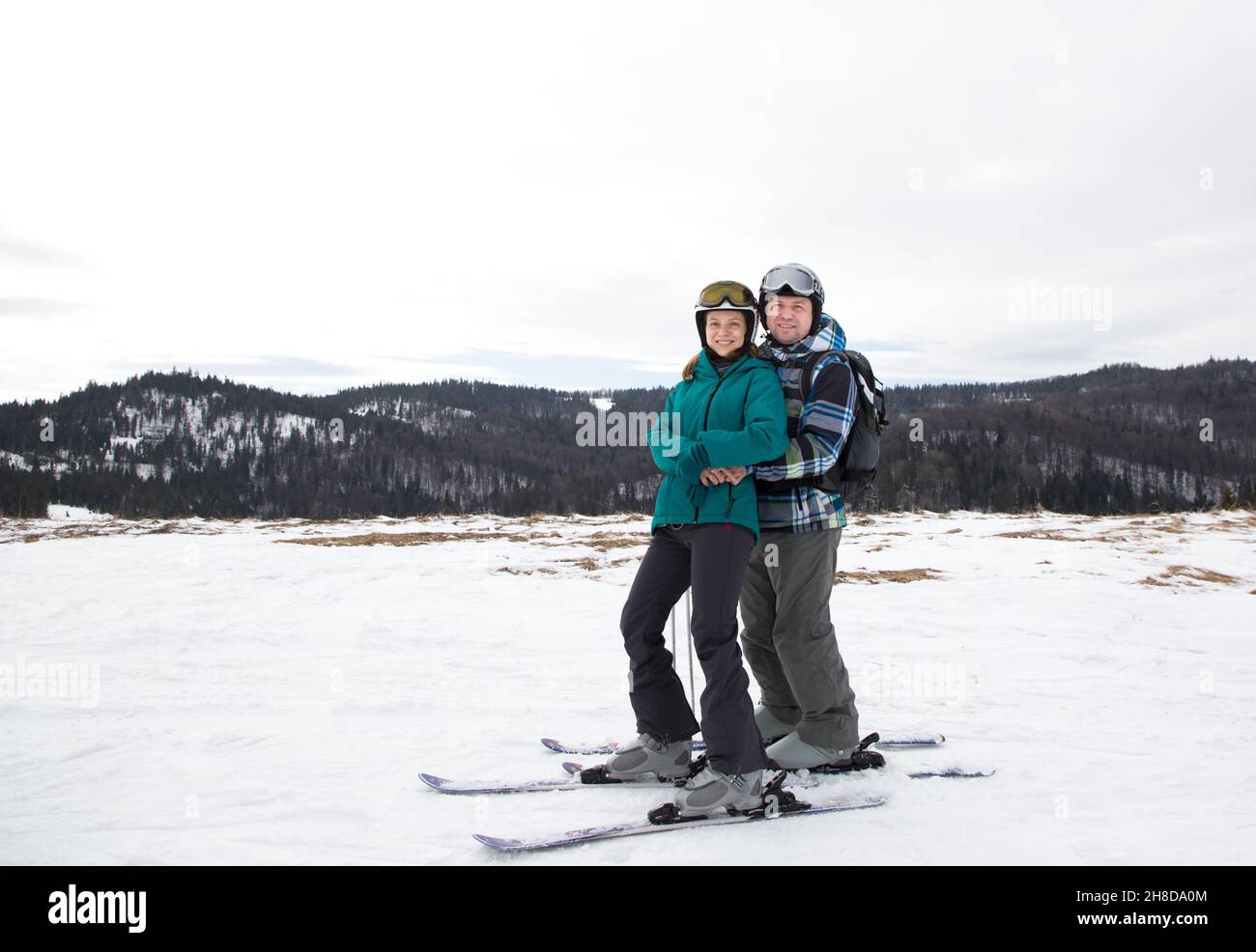 una pareja amorosa se plantea para hacer una foto antes de esquiar en una ladera nevada. Conduzca hasta un complejo de montaña el día de San Valentín. Disfrute de la relación. Interesti Foto de stock