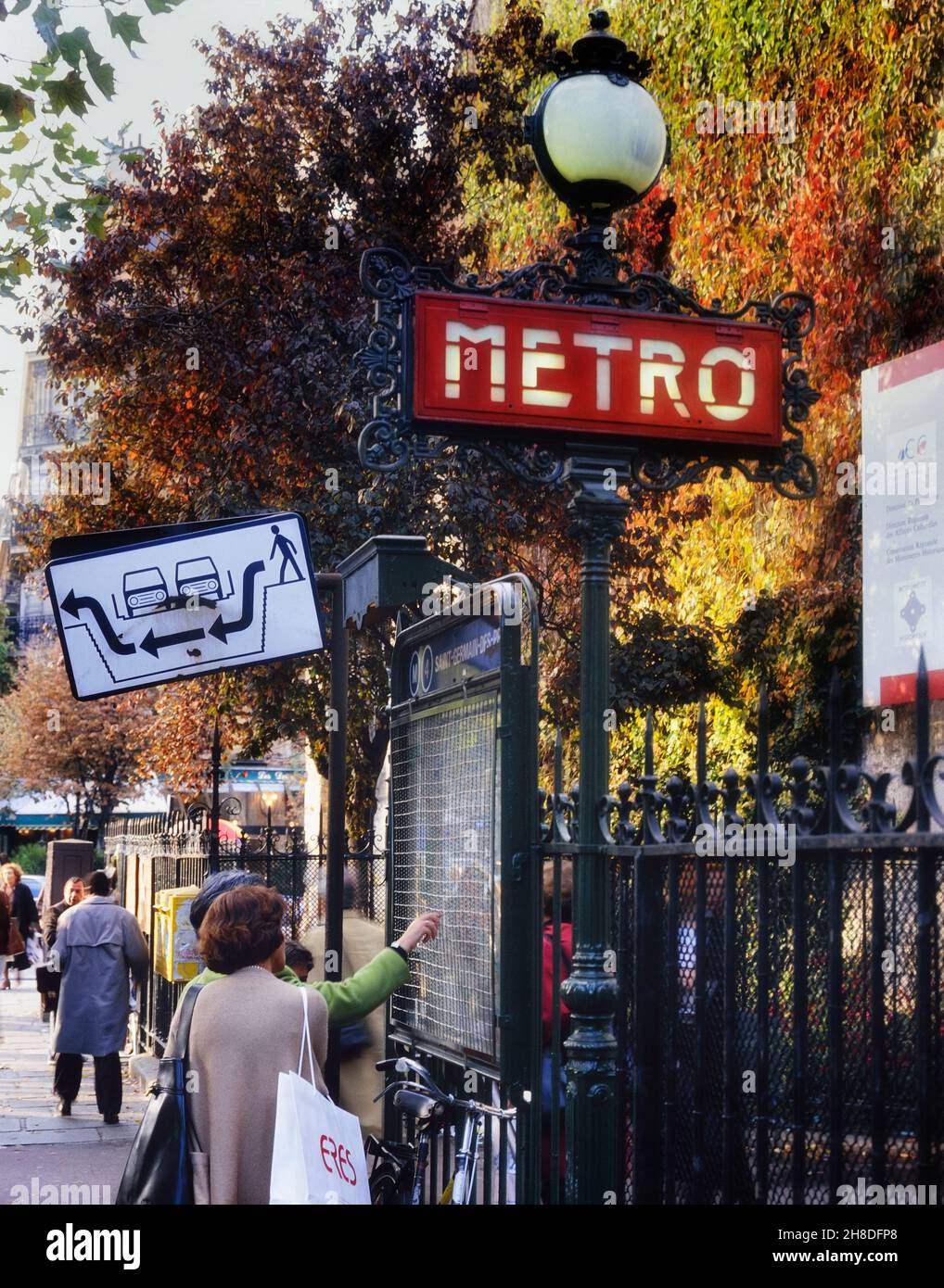 Personas que comprueban el mapa del metro fuera de la entrada a la estación Saint-Germain-des-Prés, París, Francia. Foto de stock