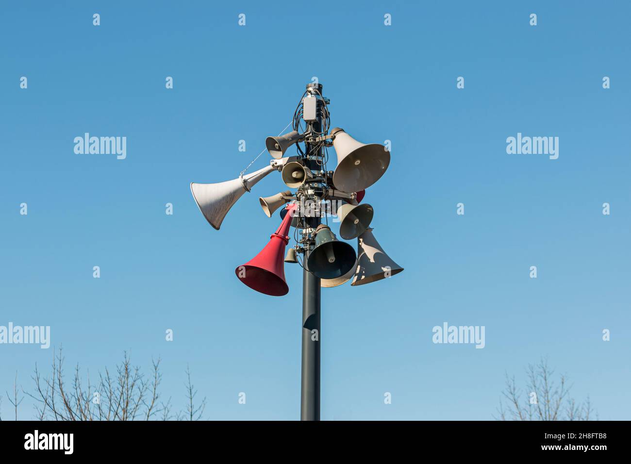 Megáfonos en un poste con fondo azul cielo, sistema de megafonía de estilo antiguo, altavoces en torre alta, sistema de advertencia. Foto de stock