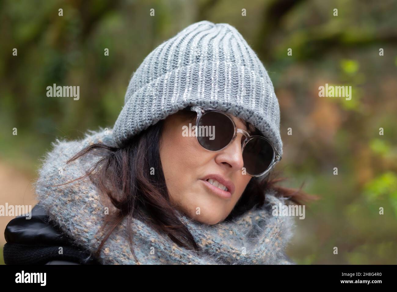retrato de una mujer con gafas de sol y sombrero de lana en el bosque en un día de otoño por la mañana - retrato de cerca Foto de stock