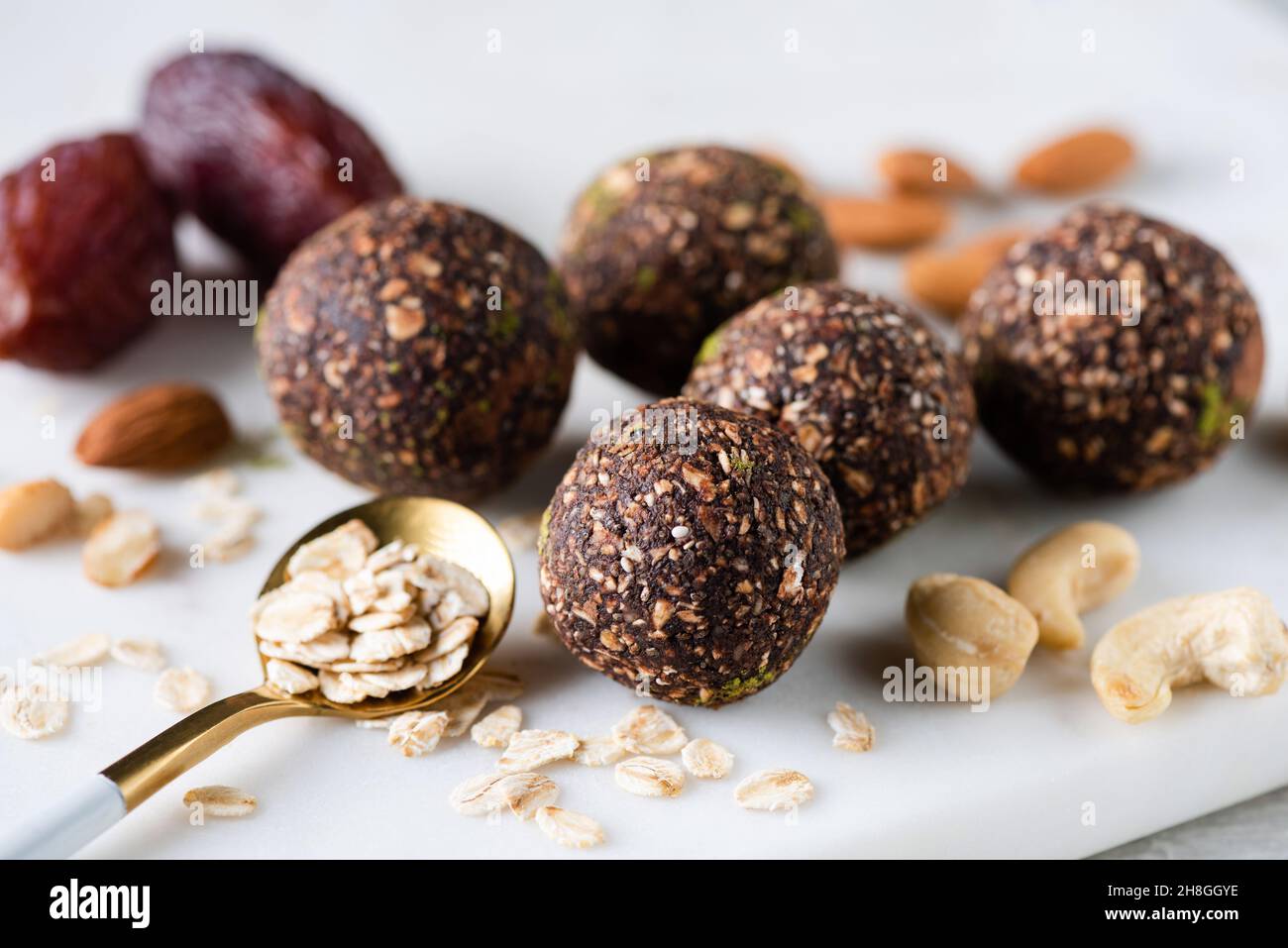 Bolas veganas de energía de chocolate hechas de nueces de anacardo, almendras, copos de avena, dátiles y polvo de algarrobo Foto de stock