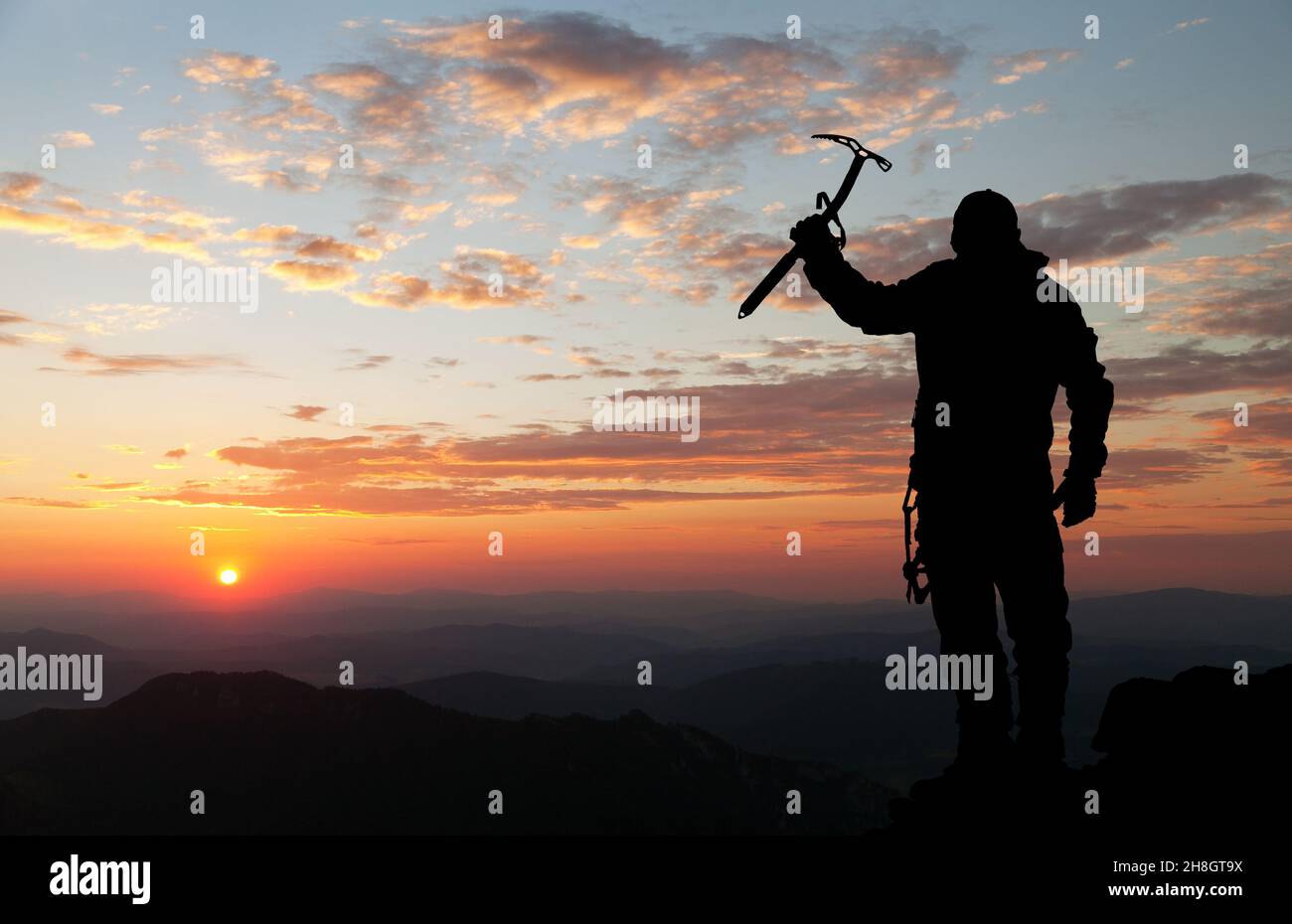 Silueta de la tarde - vista del hombre en las montañas con hielo hacha en la mano Foto de stock