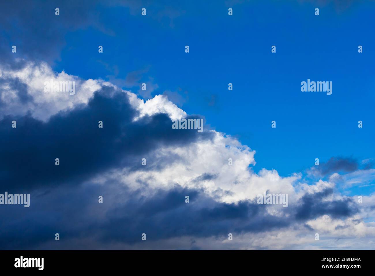 Luz dramática y nubes oscuras contra un cielo azul de verano. Textura de fondo de concepto de atmósfera peligrosa. Foto de stock