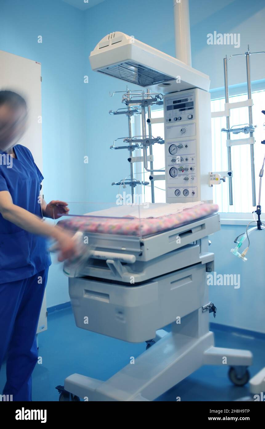 El trabajador médico permanece junto a la incubadora del bebé en el hospital. Foto de stock