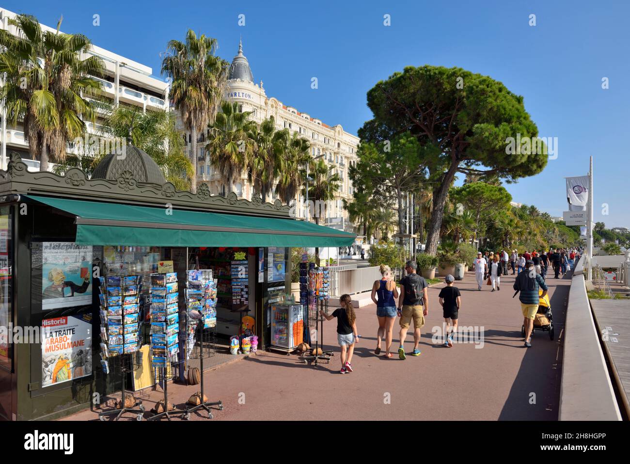 Francia, Alpes Marítimos, Cannes, La Croisette, un largo paseo marítimo con palmeras y pinos y el Carlton Hotel en el fondo Foto de stock