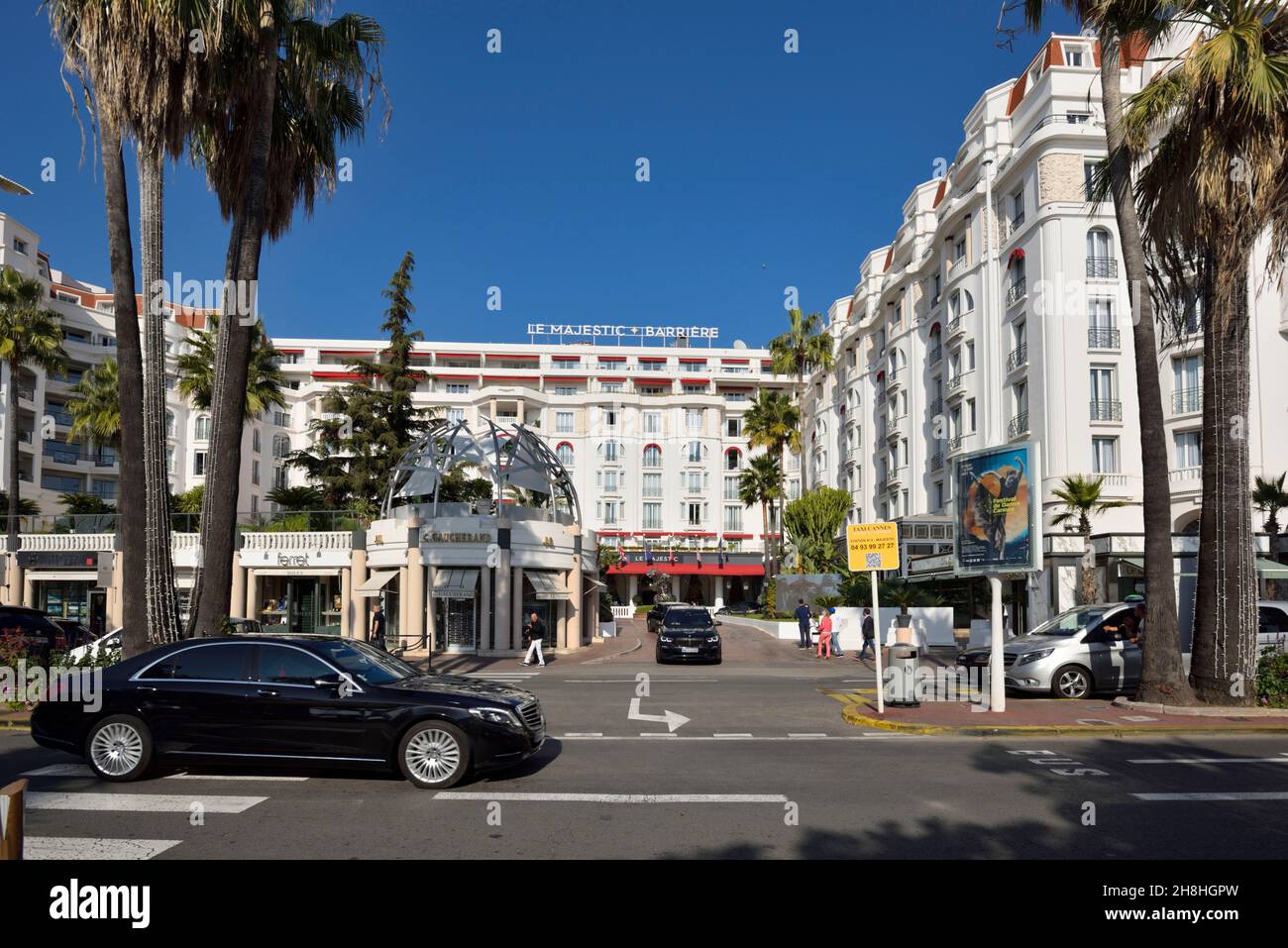 Francia, Alpes Marítimos, Cannes, La Croisette, un largo paseo marítimo con palmeras y pinos y el Majestic Barrière Hotel Foto de stock