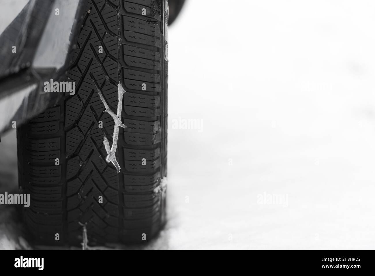 Derretimiento de nieve en el dibujo de la banda de rodadura del neumático de invierno en el coche con nieve y espacio libre en el fondo Foto de stock