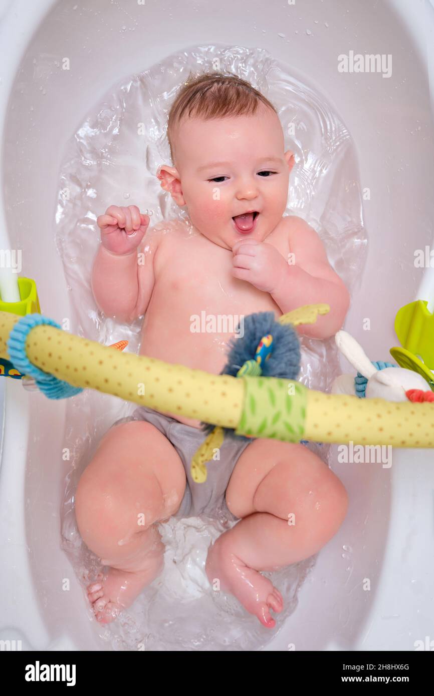 El bebé infantil juega con juguetes mientras está acostado en un baño Un bebé a la edad de cuatro meses se baña en agua Fotografía de stock - Alamy