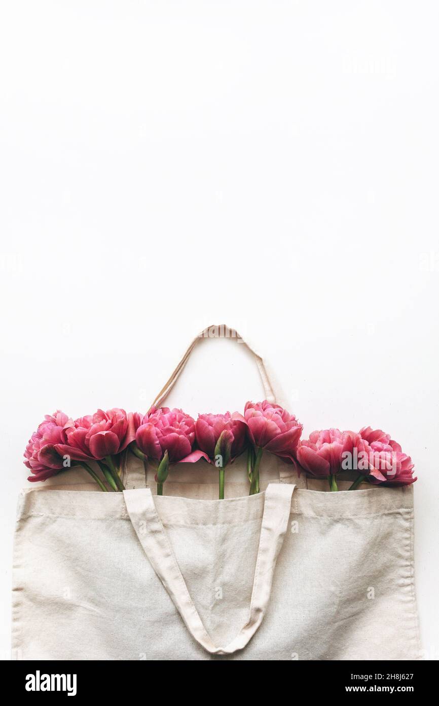 Ramo de tulipanes rosas en una bolsa de lona sobre fondo blanco. Plano, vista superior. Foto de stock