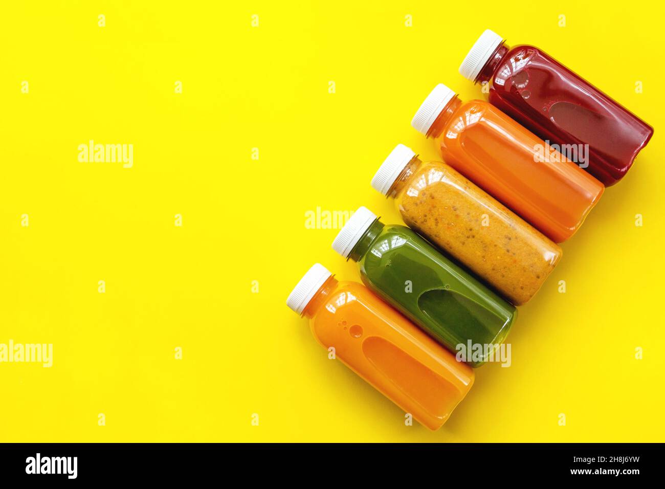 Zumos frescos o cócteles de frutas y verduras en botellas sobre fondo amarillo. El concepto de una dieta o dieta saludable. Ingredientes orgánicos frescos. Plano, vista superior Foto de stock