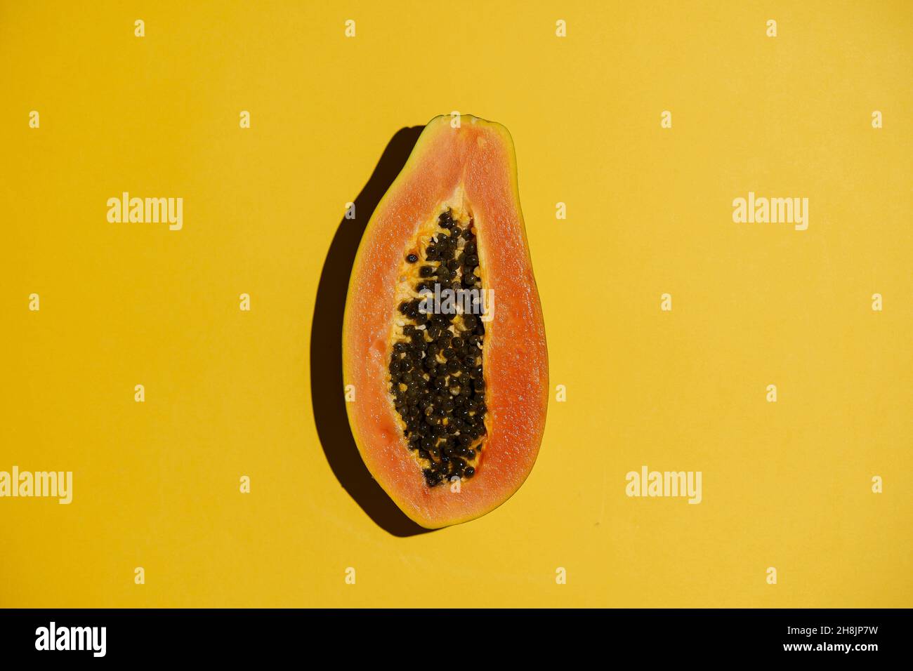 Papaya comida de verano de fondo. Jugosa y exótica papaya tropical sobre una superficie de color amarillo vacío. Verano, vitaminas, fruta, concepto de sol. Fotografías de alta calidad Foto de stock