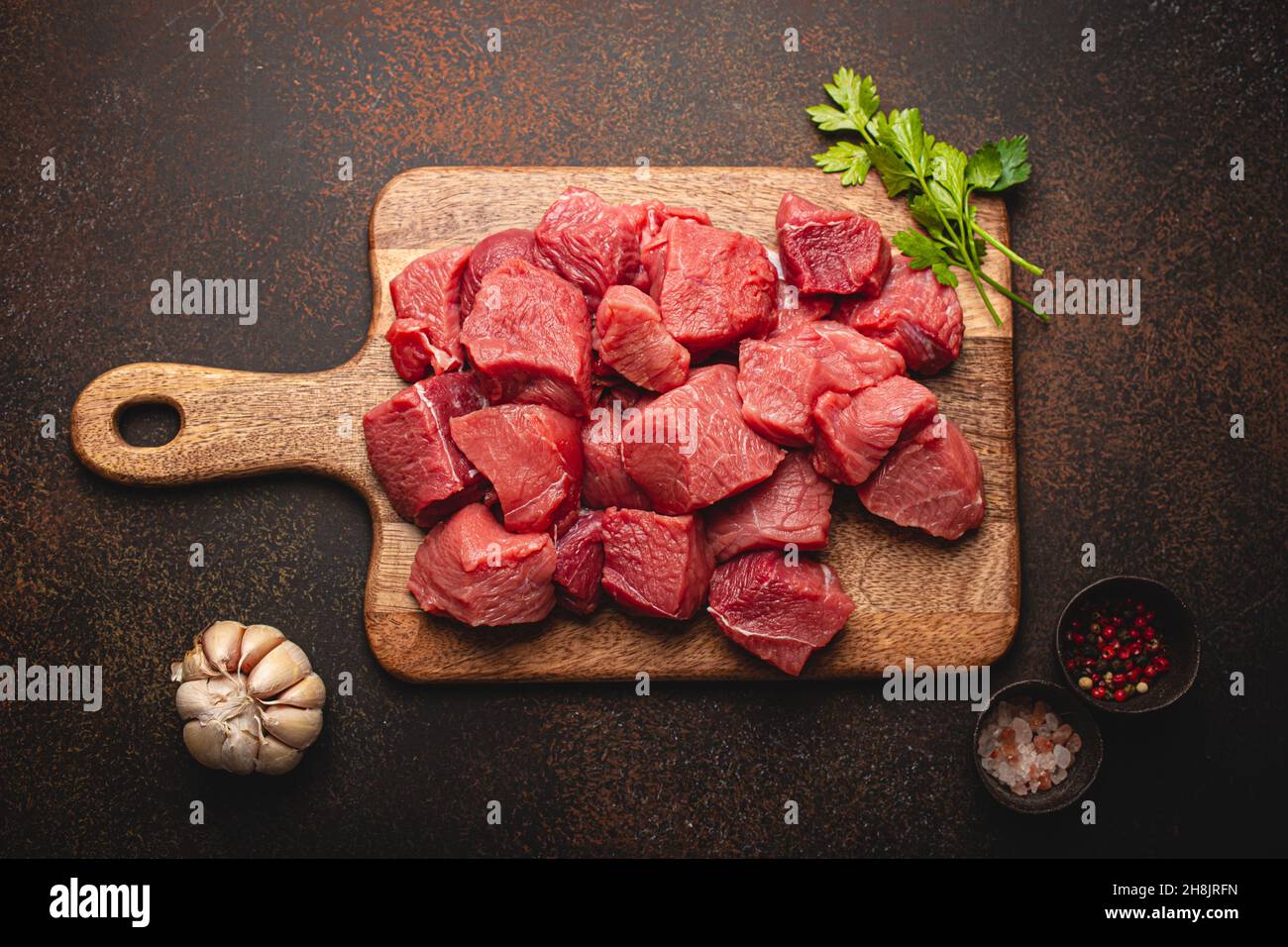 Dados de carne cruda de ternera para guisar sobre tabla de cortar de madera  Fotografía de stock - Alamy