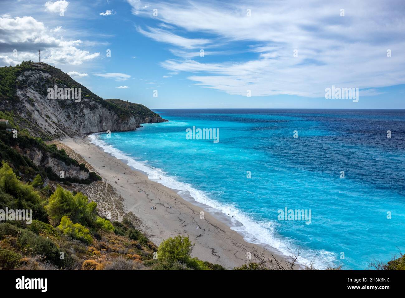 Azul olas vibrantes en la escarpada costa rocosa verde de la isla de Lefkada. Playa de arena de Mylos con un paisaje de nubes épico en Grecia. Vacaciones de verano naturaleza viaje a I Foto de stock
