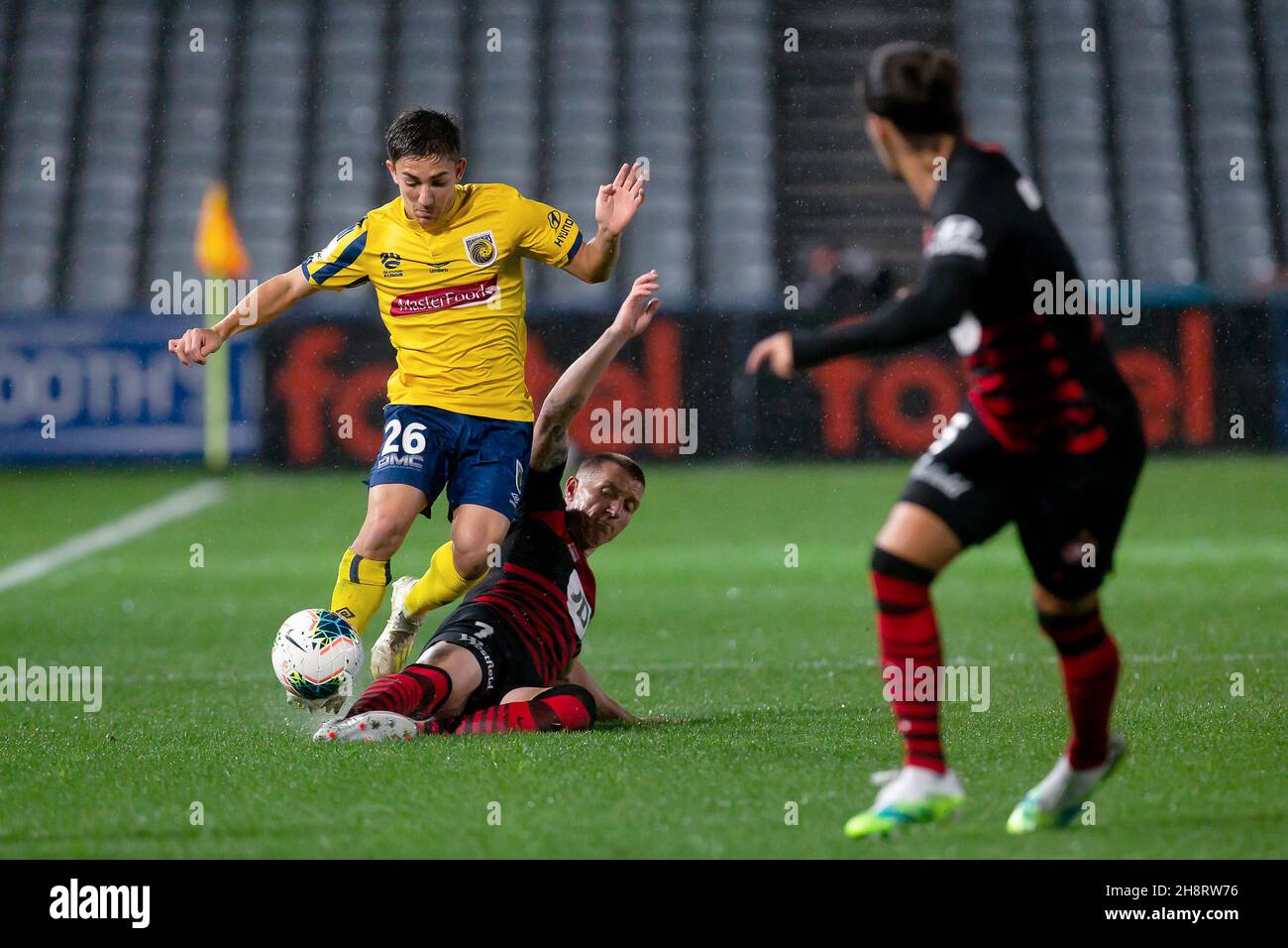 Los Wanderers del oeste de Sydney avancen hacia Mitchell Duke (7) se deslizan para enfrentarse al centrocampista Joshua Nisbet de Central Coast Mariners (26) Foto de stock