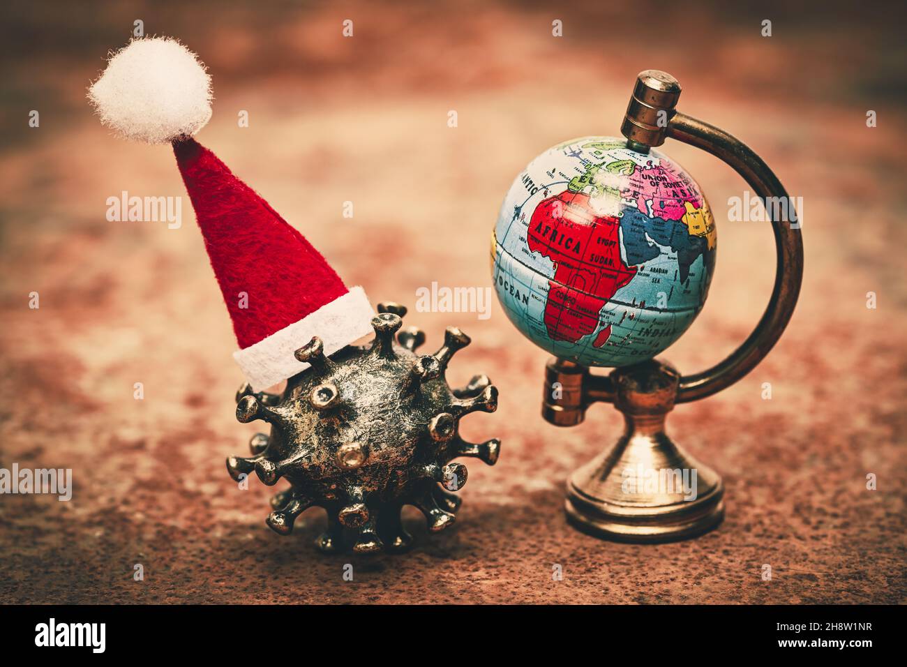 El virus de la corona lleva un sombrero de Santa cerca de un globo Foto de stock