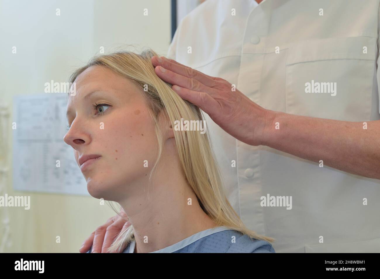 Un quiropráctico masculino ajusta la cabeza, el cuello y la columna vertebral de una paciente femenina. Inglaterra, Reino Unido Foto de stock