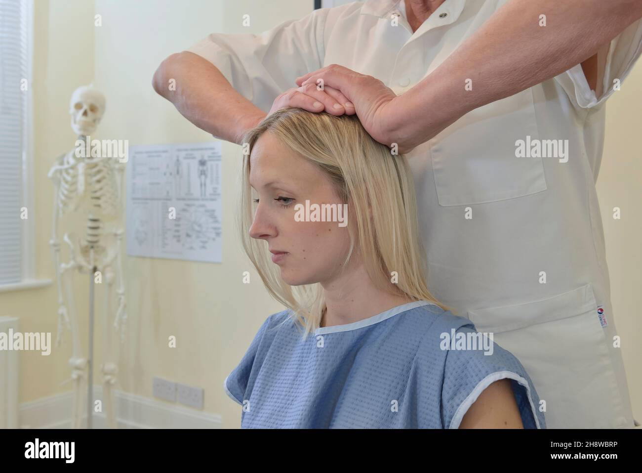 Un quiropráctico masculino ajusta la cabeza, el cuello y la columna vertebral de una paciente femenina. Inglaterra, Reino Unido Foto de stock