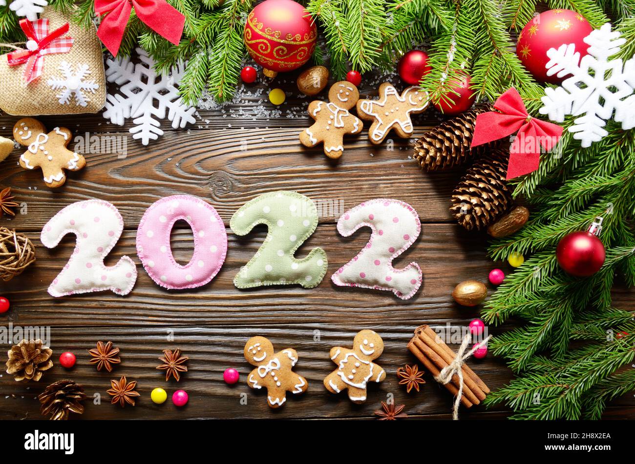 Coloridos dígitos cosidos 2022 de tela polkadot con adornos navideños plano sobre fondo de madera Foto de stock