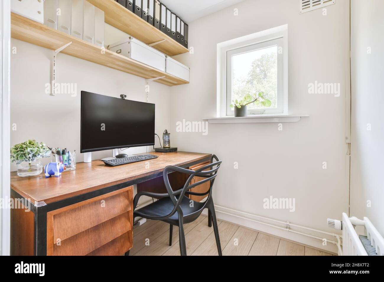 Habitación pequeña y cómoda con una mesa y un ordenador Foto de stock