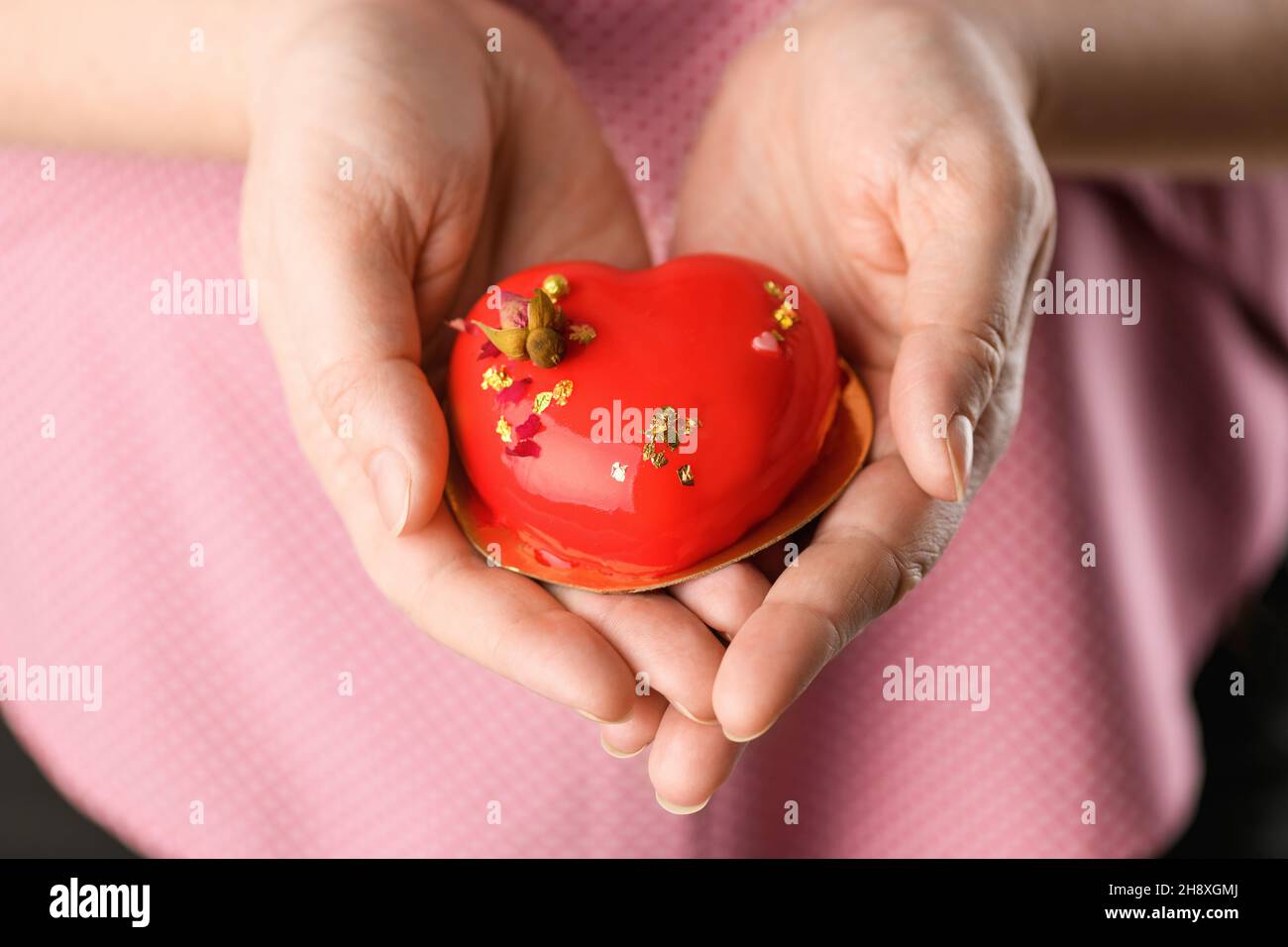 Cupcake en forma de corazón primer plano. Mousse pastel en forma de corazón en las manos de una chica para el día de San Valentín y 14th de febrero Foto de stock
