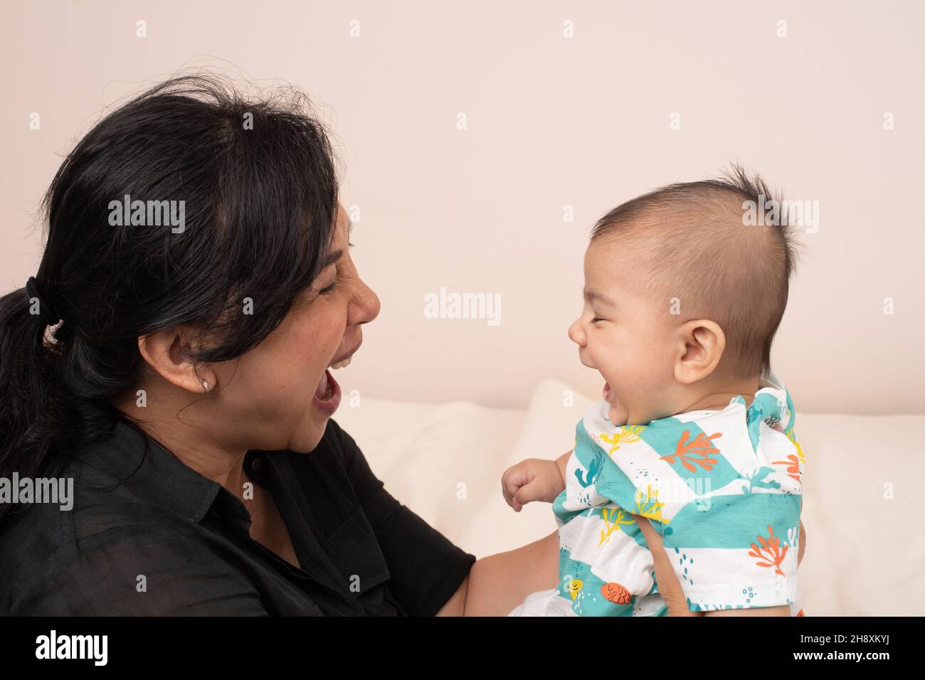 3 meses de edad bebé niño interacción con la madre que coincide con las expresiones, reír, boca abierta Foto de stock